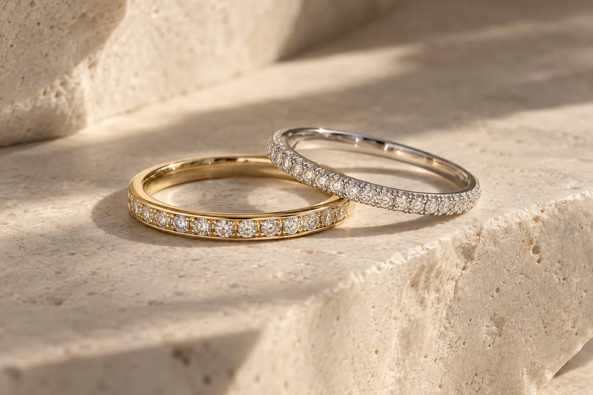 Yellow-gold channel-set and white-gold pavé moissanite wedding bands on ivory stone